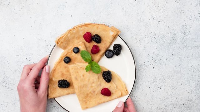 Stop motion animation with blinis or crepes with berries on plate. Top view of serving plate of blini or french crepes