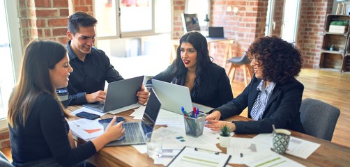 Group of business workers smiling happy and confident. Working together with smile on face  using laptop and speaking at the office