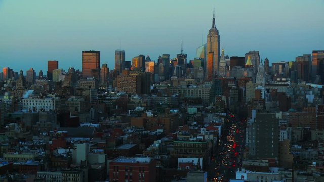 Golden hour light on Manhattan skyline with traffic on streets fades to blue hour and evening. Day to night time lapse view of New York City at sunset as day changes to night.