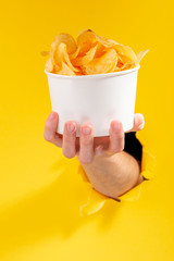 Fototapeta na wymiar Hand holding a whole cup of potato chips
