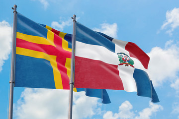Dominican Republic and Aland Islands flags waving in the wind against white cloudy blue sky together. Diplomacy concept, international relations.