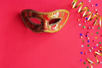Festive mask with decor on a red background. Carnival celebration concept, Mardi Gras, Brazilian carnival, Venice carnival, carnival costume, spring. Flat lay, top view, place for text