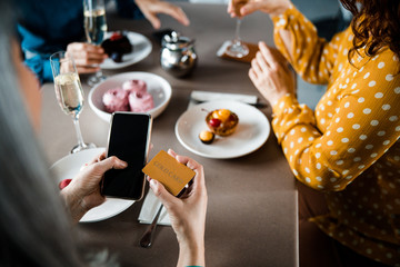 Lady paying for order in cafe with cellphone