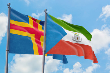 Equatorial Guinea and Aland Islands flags waving in the wind against white cloudy blue sky...