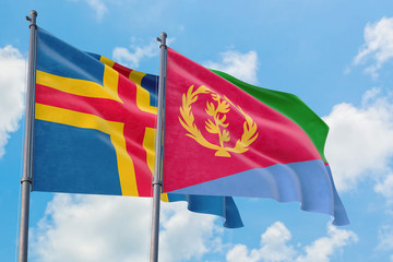 Eritrea and Aland Islands flags waving in the wind against white cloudy blue sky together. Diplomacy concept, international relations.