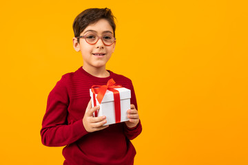 caucasian boy with gift box on yellow background with copy space