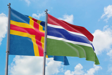 Gambia and Aland Islands flags waving in the wind against white cloudy blue sky together. Diplomacy concept, international relations.