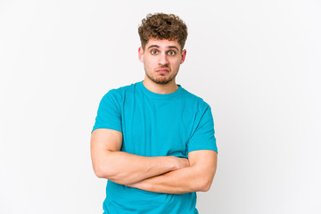 Fototapeta premium Young blond curly hair caucasian man isolated unhappy looking in camera with sarcastic expression.