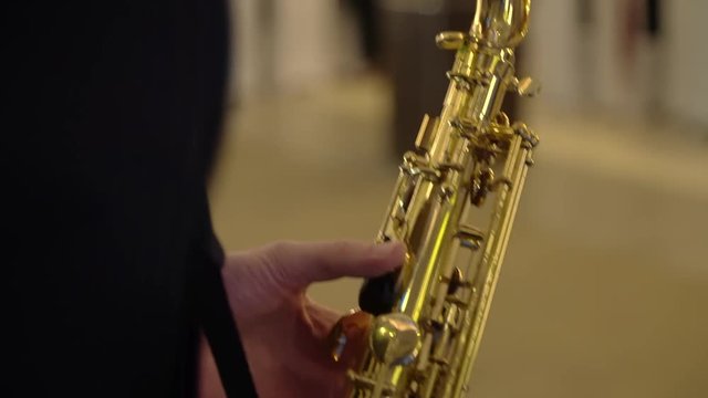 Shimmering saxophone playing, guy’s hands playing saxophone. CloseUp shot. Bokeh effect in background