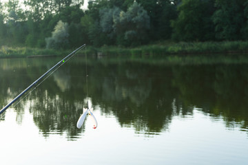 Fototapeta na wymiar Carp fishing on beautiful blue lake with carp rods and rod pods in the summer morning. Fishing from the wooden platform.