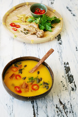 Freshly made creamy pumpkin soup served in coconut bowls with asian seasonings and pumpkin seeds