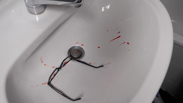 Murderer throwing blood covered spectacles evidence in sink in slow motion 