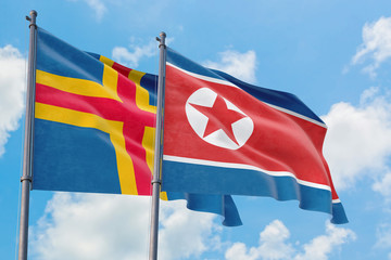 North Korea and Aland Islands flags waving in the wind against white cloudy blue sky together. Diplomacy concept, international relations.