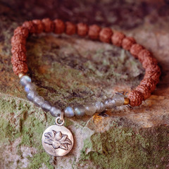 natural labradorite beads and rudraksha seed beads bracelet with lotus pendant on rocky background