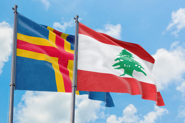 Lebanon and Aland Islands flags waving in the wind against white cloudy blue sky together. Diplomacy concept, international relations.
