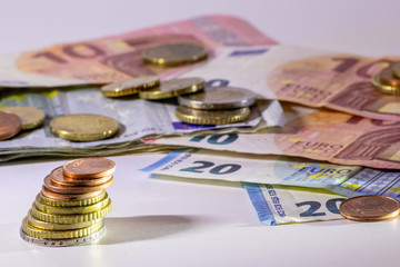 Stapel Euro-Münzen aus 2 Euro, 1 Euro und Cent-Münzen mit einem Haufen Bargeld aus Geldscheinen und EURO-Münzen zeugt von Reichtum in der Finanzwelt und schnelles Geld