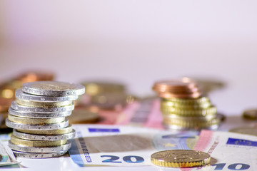 Stapel Euro-Münzen aus 2 Euro, 1 Euro und Cent-Münzen mit einem Haufen Bargeld aus Geldscheinen und EURO-Münzen zeugt von Reichtum in der Finanzwelt und schnelles Geld