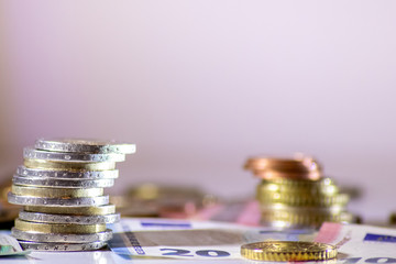 Stapel Euro-Münzen aus 2 Euro, 1 Euro und Cent-Münzen mit einem Haufen Bargeld aus Geldscheinen...