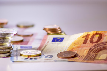 Stapel Euro-Münzen aus 2 Euro, 1 Euro und Cent-Münzen mit einem Haufen Bargeld aus Geldscheinen und EURO-Münzen zeugt von Reichtum in der Finanzwelt und schnelles Geld