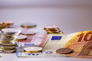 Stapel Euro-Münzen aus 2 Euro, 1 Euro und Cent-Münzen mit einem Haufen Bargeld aus Geldscheinen und EURO-Münzen zeugt von Reichtum in der Finanzwelt und schnelles Geld