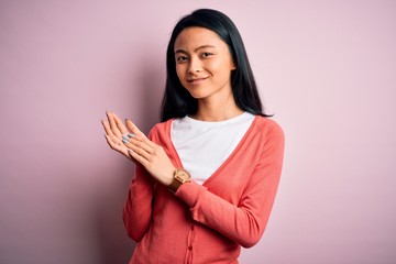 Obraz premium Young beautiful chinese woman wearing casual sweater over isolated pink background clapping and applauding happy and joyful, smiling proud hands together