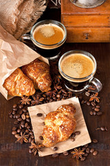 Glass  mug of coffee  and  croissants on wooden table 