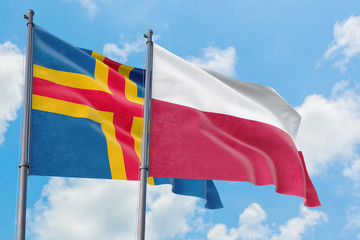 Poland and Aland Islands flags waving in the wind against white cloudy blue sky together. Diplomacy concept, international relations.