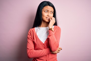 Young beautiful chinese woman wearing casual sweater over isolated pink background looking stressed...