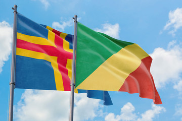 Republic Of The Congo and Aland Islands flags waving in the wind against white cloudy blue sky together. Diplomacy concept, international relations.