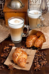 Glass  mug of coffee  and  croissants on wooden table 