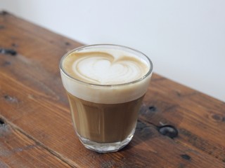 A cup of coffee with latte art, a cappuccino or a moka rich in caffeine with some milk, on the table in a trendy hipster cafe.