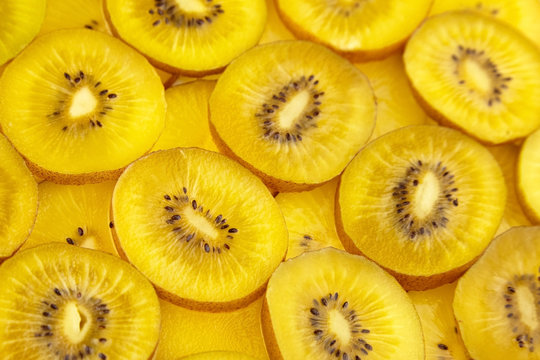 Kiwi Gold fruit background. Yellow kiwi slices with black seeds, closeup