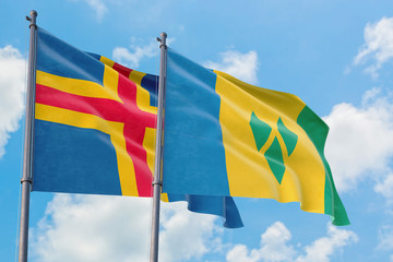 Saint Vincent And The Grenadines and Aland Islands flags waving in the wind against white cloudy blue sky together. Diplomacy concept, international relations.