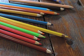 Colored pencils lying on the wooden table, ready to draw and make art as part of creative hobby and...