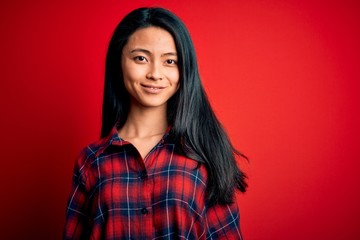 Young beautiful chinese woman wearing casual shirt over isolated red background with a happy and...