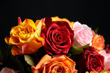 Bouquet of different color roses with water drops on petals on a black background. Red, orange and pink flowers. Romantic Valentine's Day Gift