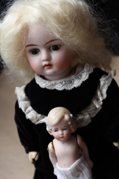 Two beautiful girl dolls, antique toys from porcelain made in Germany, portrayed as two sisters, an older and younger one.