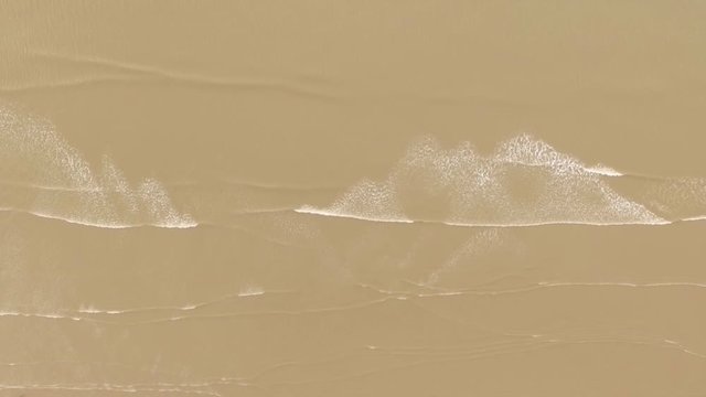 Aerial drone Seaside beach top down of waves headed toward shore