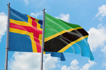 Tanzania and Aland Islands flags waving in the wind against white cloudy blue sky together. Diplomacy concept, international relations.