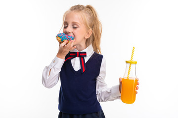 Pretty schoolgirl eats a donut and drinks juice isolated on white background