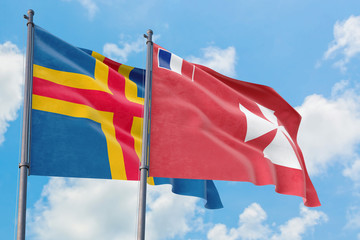 Wallis And Futuna and Aland Islands flags waving in the wind against white cloudy blue sky together. Diplomacy concept, international relations.