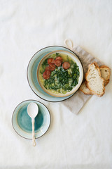 Caldo Verde Soup with greens and chopped chorizo on the top in ceramic bowl.