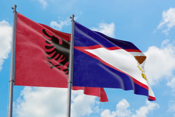 American Samoa and Albania flags waving in the wind against white cloudy blue sky together. Diplomacy concept, international relations.