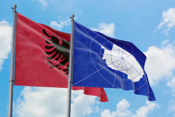 Antarctica and Albania flags waving in the wind against white cloudy blue sky together. Diplomacy concept, international relations.