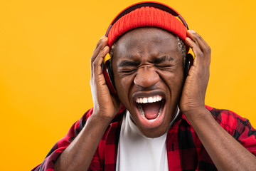 closeup portrait of an embarrassed stylish black man screaming in red headphones
