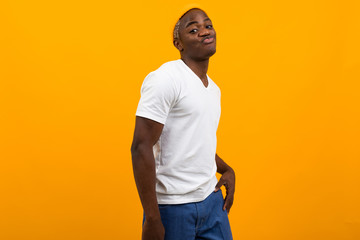 smiling american black man in white t-shirt on yellow background with copy space