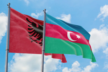 Azerbaijan and Albania flags waving in the wind against white cloudy blue sky together. Diplomacy concept, international relations.