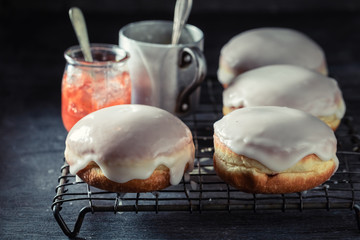 Tasty donuts with red jam on dark table