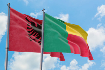 Benin and Albania flags waving in the wind against white cloudy blue sky together. Diplomacy concept, international relations.