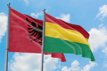 Bolivia and Albania flags waving in the wind against white cloudy blue sky together. Diplomacy concept, international relations.